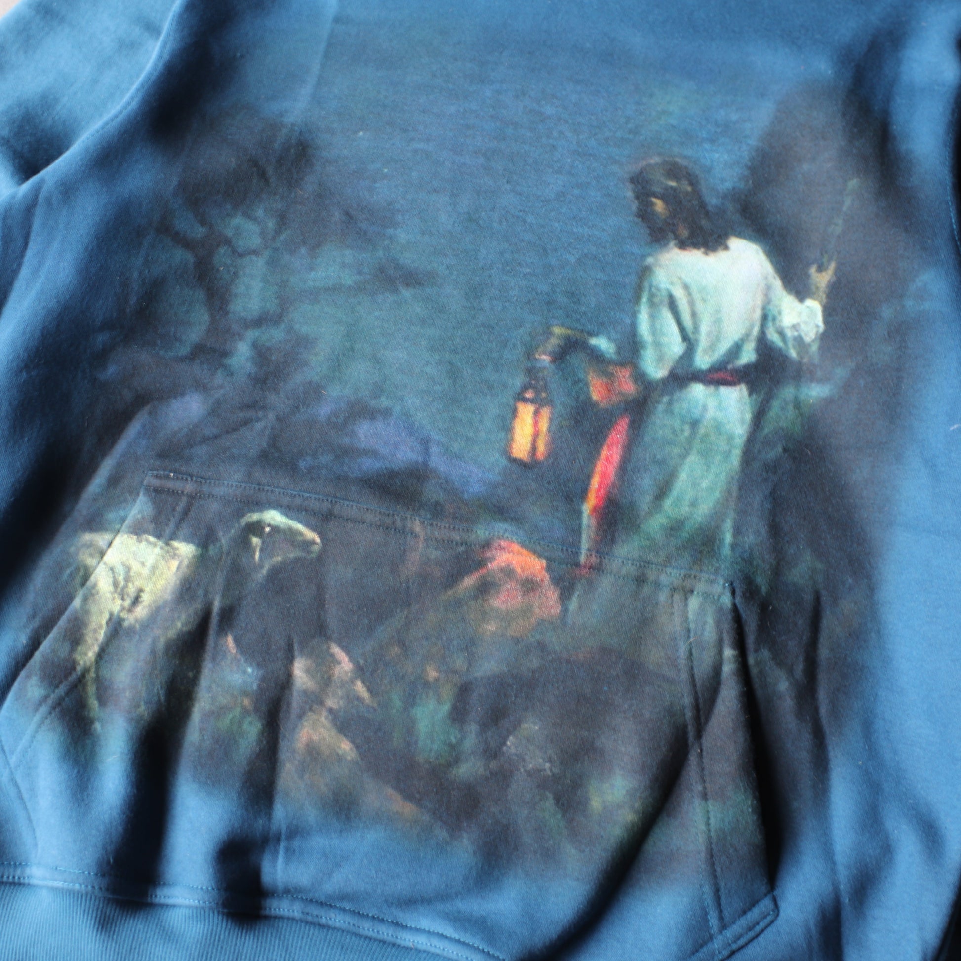 Blue sweatshirt with a graphic design of a person holding a lantern and a dog on a leash.